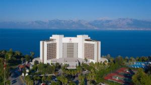 une vue aérienne sur un grand bâtiment blanc avec des montagnes en arrière-plan dans l'établissement Akra Antalya, à Antalya