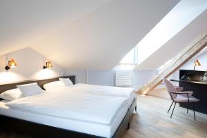 a bedroom with a large white bed and a chair at Hotel Schützen Rheinfelden in Rheinfelden