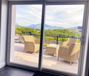 einen Balkon mit Stühlen und Bergblick in der Unterkunft Bryn Mair cottage overlooking Snowdon in Caernarfon