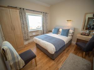 een slaapkamer met een bed, een stoel en een raam bij Ceol na Mara Guest House in Enniscrone