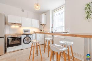 a kitchen with white cabinets and a counter with stools at matcha home Hettange in Hettange-Grande