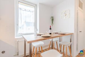 a white kitchen with a wooden table and white stools at matcha home Hettange in Hettange-Grande