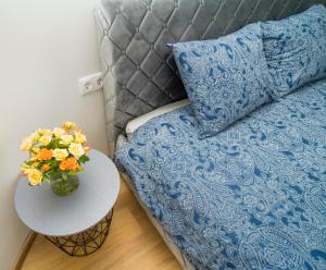 un lit avec une couverture bleue et une table avec un vase de fleurs dans l'établissement Fort63 apartments, à Kaunas