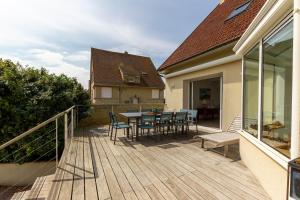 eine Holzterrasse mit einem Tisch und Stühlen auf einem Haus in der Unterkunft Villa de la Plage - à Ver sur Mer in Ver-sur-Mer