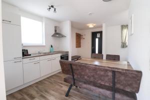 a kitchen with white cabinets and a wooden table at Black Forest Hotel Kappel-Grafenhausen in Kappel-Grafenhausen