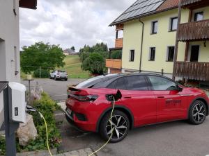 Un coche rojo está siendo cargado por una manguera amarilla en Café-Pension Feldbergblick, en Titisee-Neustadt