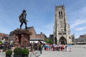 um grupo de pessoas em pé em torno de uma estátua em frente a uma catedral em Viator Holidayhome em Tongeren