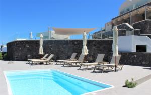 a swimming pool with chairs and umbrellas on a patio at Alegria by Casa Sigalas in Oia