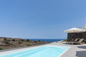 a villa with a swimming pool and an umbrella at Alegria by Casa Sigalas in Oia