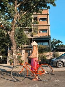 ホイアンにあるKaia Gallery Hotel Hoi Anの自転車の横に立つ帽子の女