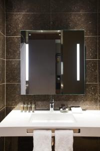 bagno con lavandino bianco e specchio di AC Hotel Cincinnati at Liberty Center a West Chester