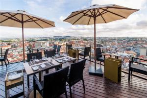 een restaurant met tafels en parasols op een balkon bij Hotel Dom Henrique - Downtown in Porto