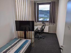 a bedroom with a bed and a desk and a television at Business-Motel, free XL-Parking, WiFi, massage-chairs, sauna, shared kitchen, breakfast 2go, free soda, coffee in Heimsheim