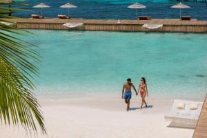 Impression Isla Mujeres by Secrets - Adults Only - All Inclusive في إيسلا موخيريس: a man and a woman walking on a beach