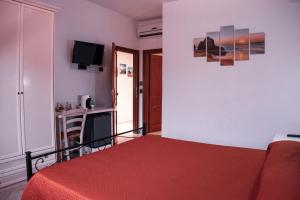 1 dormitorio con cama roja y TV en Mare Sole, en San Teodoro