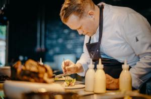 um homem numa cozinha a preparar comida num prato em Luisenhöhe - Gesundheitsresort Schwarzwald em Horben