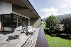 eine Terrasse mit Stühlen und Tischen an der Seite eines Hauses in der Unterkunft Astor Apartments in Olang