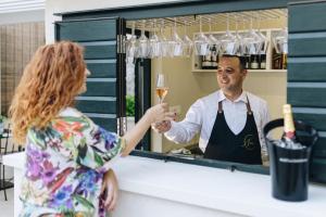 a woman is handing a man a glass of wine at Sperone Hotel in Split