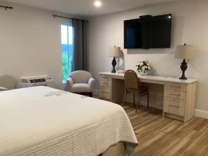 a hotel room with a bed and a desk with a tv at Lunenburg Arms Hotel in Lunenburg