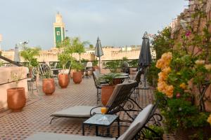 un balcone con tavoli, sedie e una torre dell'orologio. di Riad Yacout a Meknès