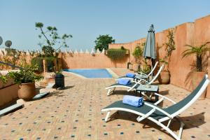 patio con sedie, ombrellone e piscina di Riad Yacout a Meknès