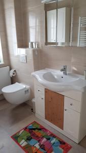 a bathroom with a sink and a toilet and a mirror at Ferienwohnung am Schlosssee. in Penkun