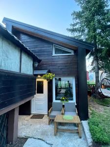 una casa pequeña con una puerta, dos sillas y una mesa en Guest House Durmitor Paradise, en Žabljak