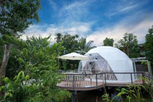 a dome tent on a deck with an umbrella at Le Villagio Resort & Domes in Sultan Bathery