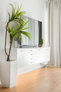 een witte kast met een tv en een potplant bij Harmony Sea View Apartment in Thessaloniki