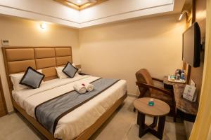 1 dormitorio con cama, mesa y TV en Hotel Grand Sabarees, en Madurai