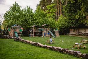 un bambino seduto su una panchina in un parco giochi di Wolkendorf Bio Hotel & Spa a Braşov