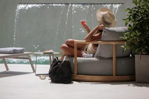 a woman sitting on a couch with a drink at Anapollo Boutique Hotel Adults Only in Naxos Chora