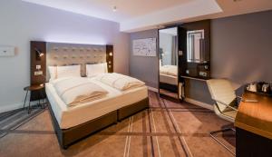 een slaapkamer met een bed, een bureau en een spiegel bij Premier Inn Stuttgart City Europaviertel in Stuttgart