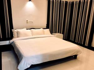 una camera da letto con un grande letto con lenzuola e cuscini bianchi di Garuda Suites a Varkala