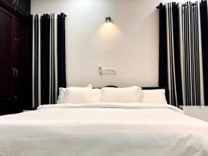 una camera da letto con un letto bianco e tende nere di Garuda Suites a Varkala