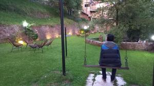 a woman sitting on a swing in a yard at LOKAL Rooms x Murree Kashmir Point in Murree