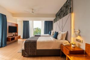 a hotel room with a large bed and a television at De Mandarin Goa in Candolim