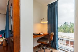 a desk with a chair next to a window at De Mandarin Goa in Candolim