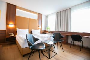 une chambre d'hôtel avec un lit, des chaises et une table dans l'établissement Das Reinisch Hotel & Restaurant, à Schwechat