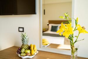 un jarrón con flores amarillas y fruta en una mesa en EPHYRA, en Sivota