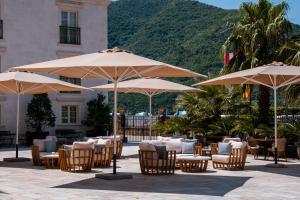 een patio met tafels, stoelen en parasols bij Heritage Grand Perast By Rixos in Perast