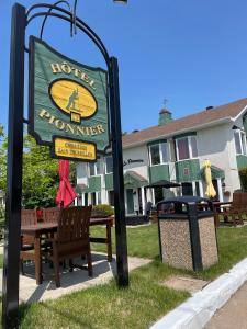 un cartello per un hotel a Houston con una panchina e un bidone della spazzatura di Hotel Le Pionnier a Tadoussac