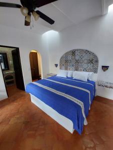 - une chambre avec un grand lit et une couverture bleue dans l'établissement Casa Yollotzin, à Ajijic