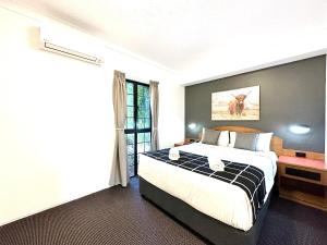 een slaapkamer met een groot bed en een raam bij Mackay Resort Motel in Mackay