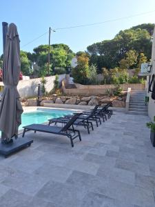 a group of lounge chairs and an umbrella next to a pool at Edith et Jean-Paul in Porto-Vecchio