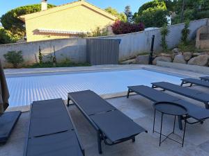 a swimming pool with three benches and a table at Edith et Jean-Paul in Porto-Vecchio