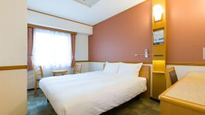 um quarto de hotel com uma cama branca e uma secretária em Toyoko Inn Sendai eki Nishi guchi Chuo em Sendai