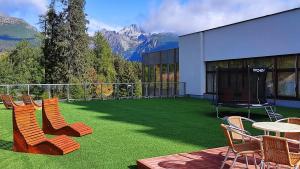 een patio met stoelen en een tafel met uitzicht op de bergen bij Hotel SOREA TRIGAN in Štrbské Pleso