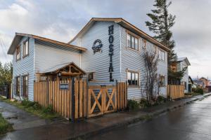 une maison blanche avec une clôture en bois dans une rue dans l'établissement Hostal Lago Cóndor, à Puerto Natales