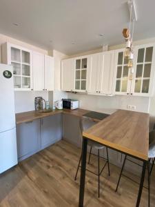 a kitchen with white cabinets and a wooden table at Апартаменты CLASSIC в жк Империал in Truskavets